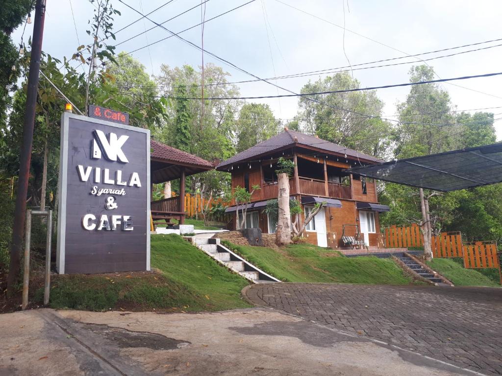una señal frente a una casa con un edificio en NK Villa Syariah And Cafe Prigen en Pasuruan