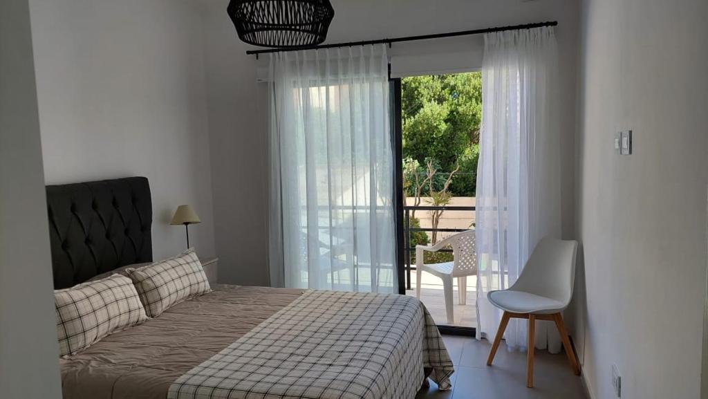 a bedroom with a bed and a sliding glass door at Departamentos del Trébol in Necochea