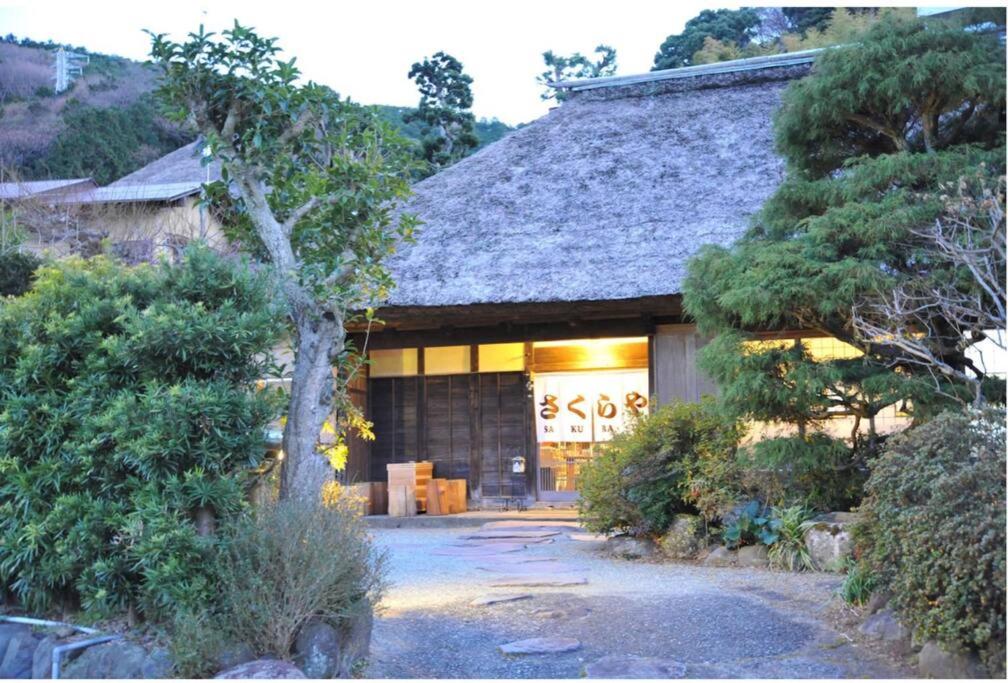 una casa con un edificio con un árbol en 古民家さくらや, en Atami