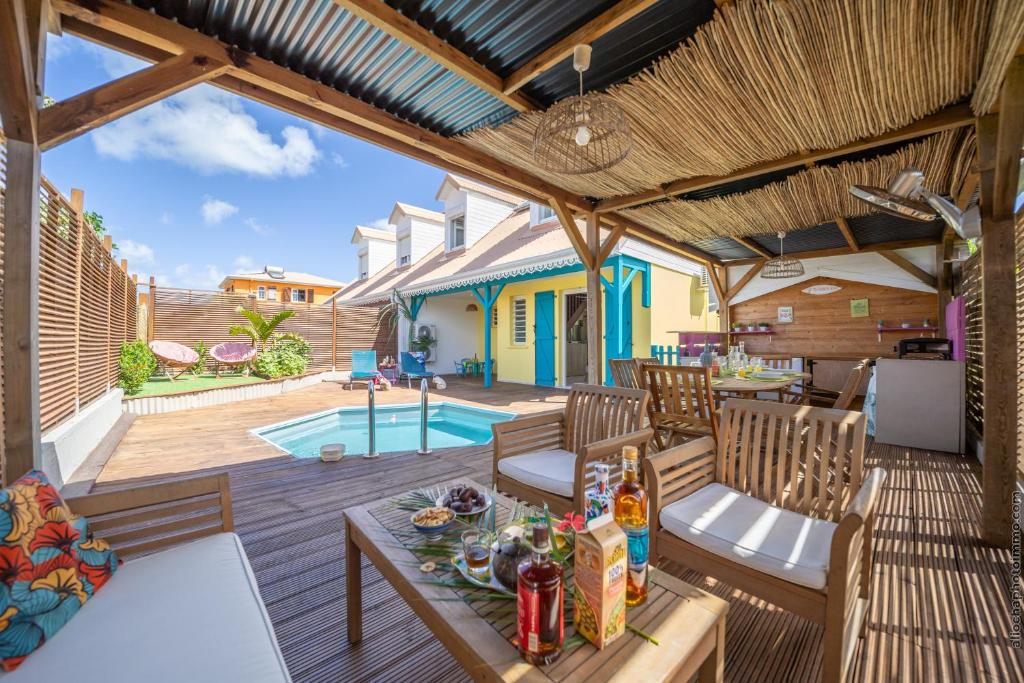 um pátio com uma mesa e cadeiras e uma piscina em Villa Kay Lakansiel, magnifique cocon familial avec piscine em Le Vauclin