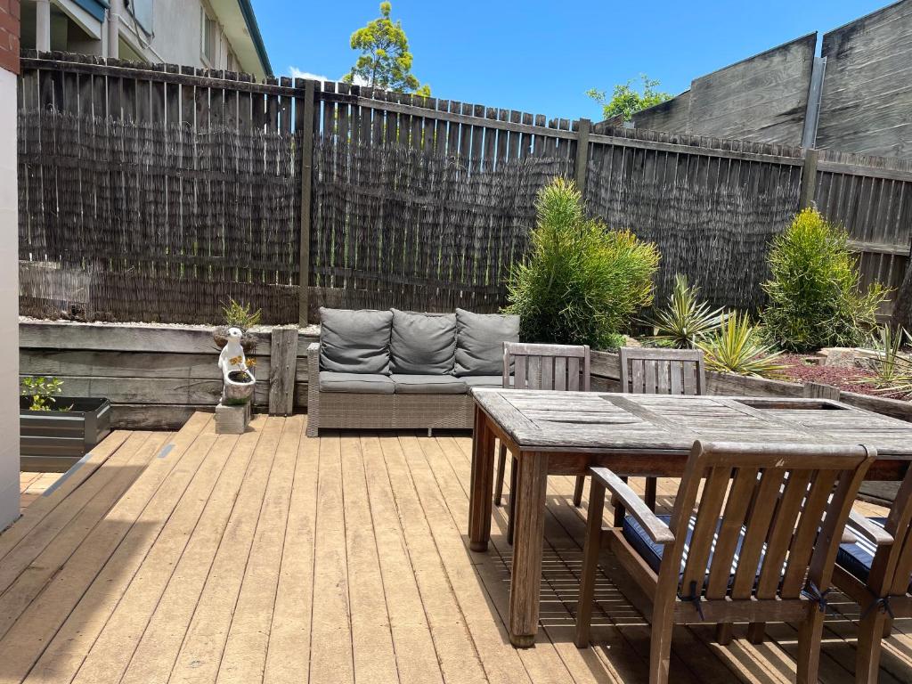 a patio with a wooden table and a couch at Yeronga Hideaway in Brisbane