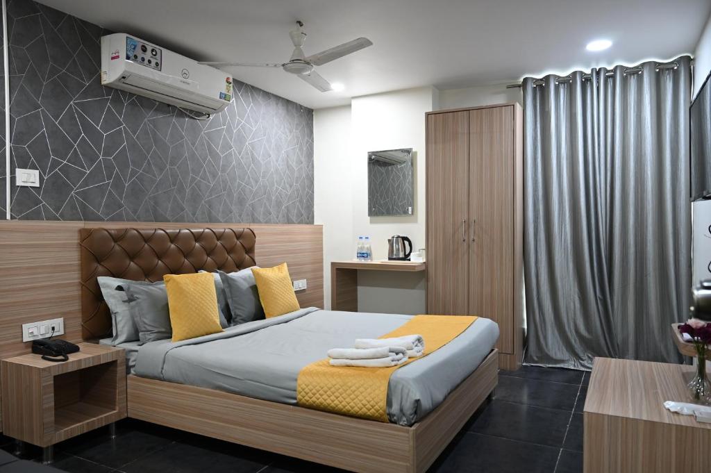 a bedroom with a bed with yellow and gray pillows at Hotel Supraja Yellow Bells in Hyderabad