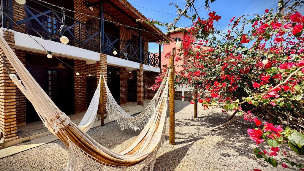 a couple of hammocks in front of a building with flowers at Suítes Bosque de Flecheiras in Flecheiras