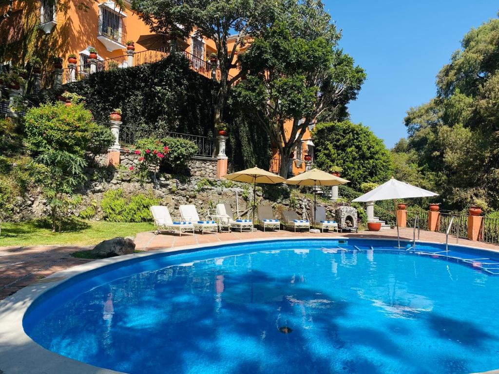 クエルナバカにあるVilla Colonial los Sabinosの青い大型スイミングプール(椅子、パラソル付)