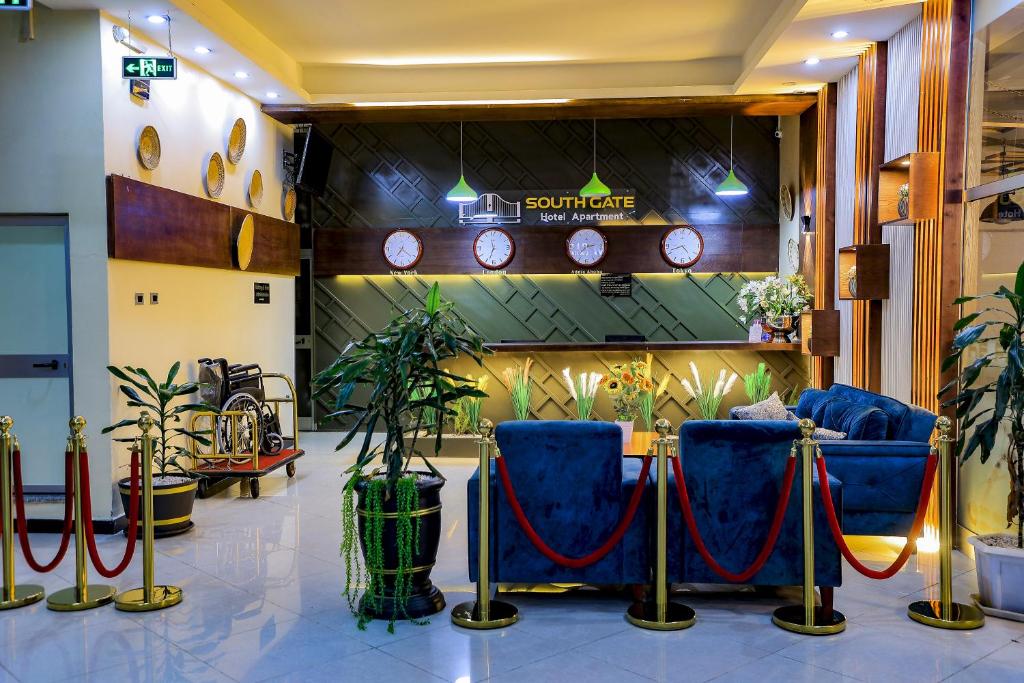 un vestíbulo con sillas y relojes en la pared en South Gate Hotel Apartment, en Addis Ababa
