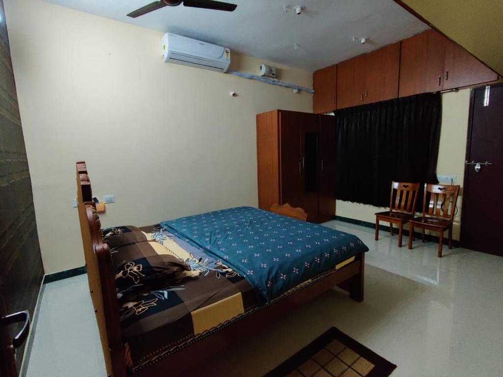 a bedroom with a bed and two chairs in it at luxury home in Vadavalli in Coimbatore