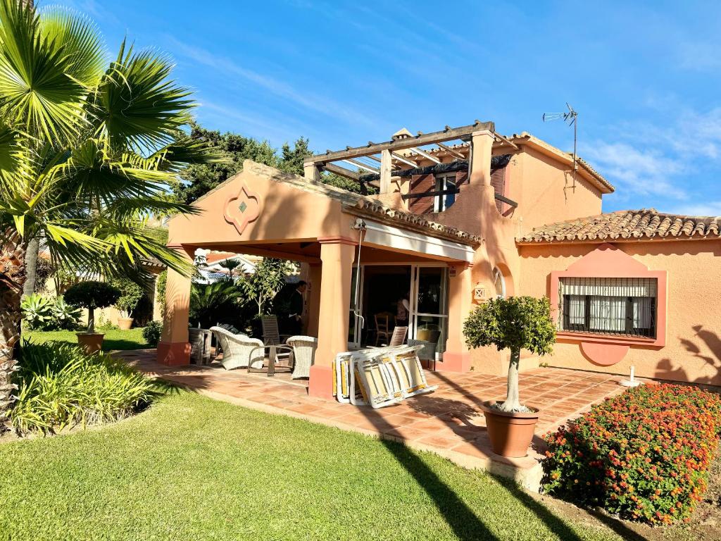 a house with a patio with chairs and a palm tree at Villa Rural junto a la playa - SUN & RELAX in Marbella