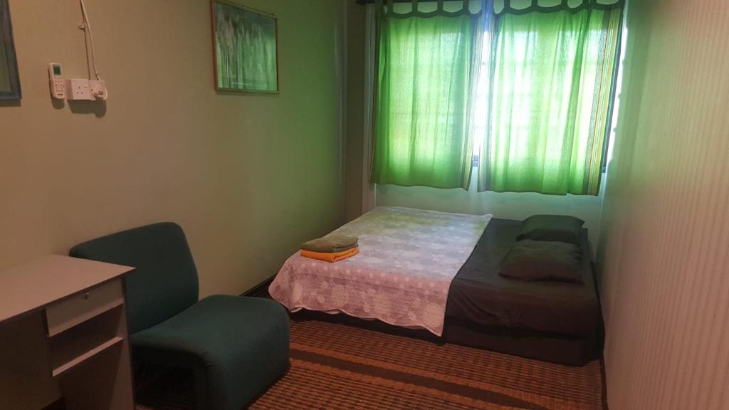 a bedroom with a bed and a desk and a window at Marco Polo Guest House in Kuching