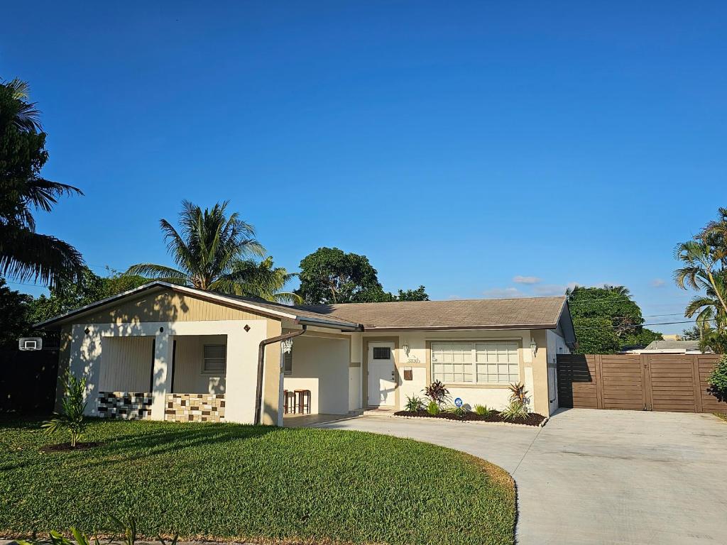 una gran casa blanca con entrada y palmeras en Sunny Goldie, en Lauderdale Lakes