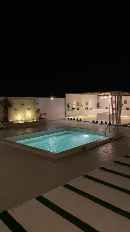 a large swimming pool in a building at night at The sunset farm in á¸¨aÅŸat al BidÄ«yah