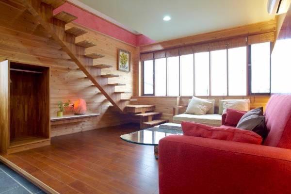 a living room with a red couch and stairs at 快樂鼠樓中樓4-6人房 in Taitung City