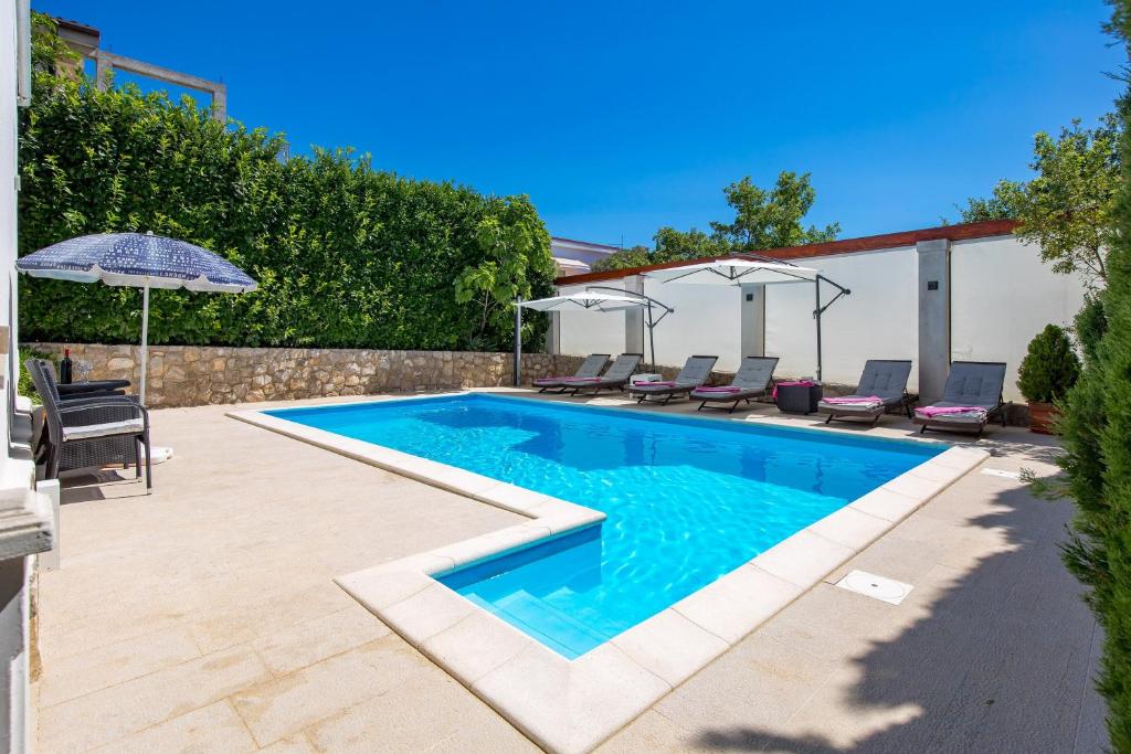 una piscina con sillas y sombrilla en Family House Rose with Pool - Happy Rentals, en Pinezici