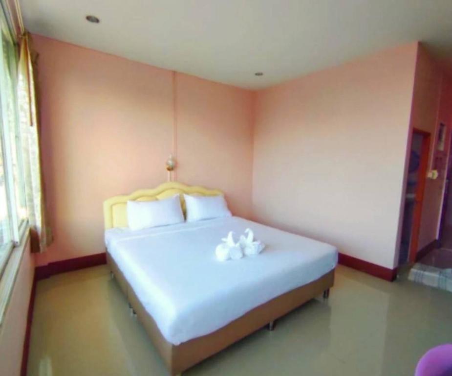 โรงเเรมคิงส์พาเลซ King's Palace HOTEL في Seka: غرفة نوم مع سرير مع وجود وردتين بيضاء عليه
