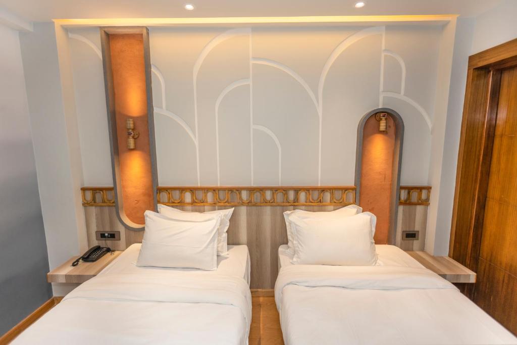 2 camas en una habitación pequeña con sábanas blancas en Ananta Home en Katmandú