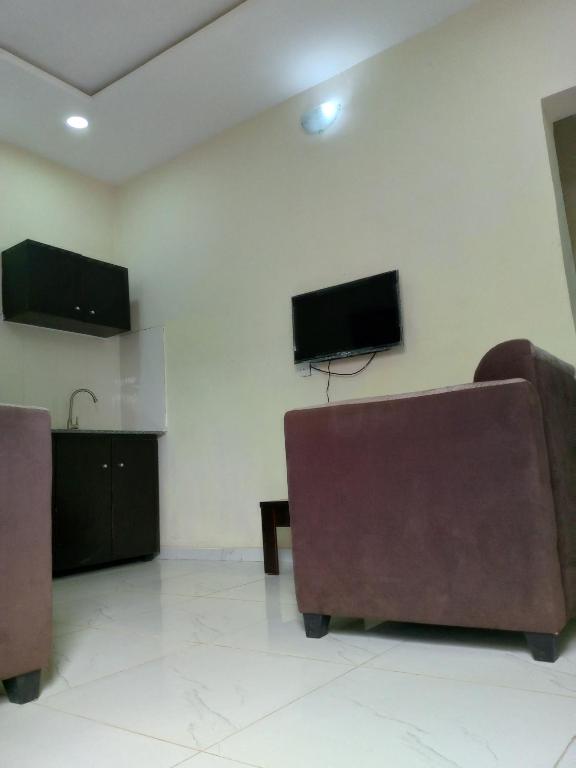 a living room with two chairs and a flat screen tv at F&B Service Apartment in Abeokuta