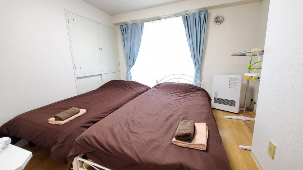 a bedroom with a bed with brown sheets and a window at 札幌市中心部大通公園まで徒歩八分観光移動に便利なロケーションe1007#17 in Sapporo