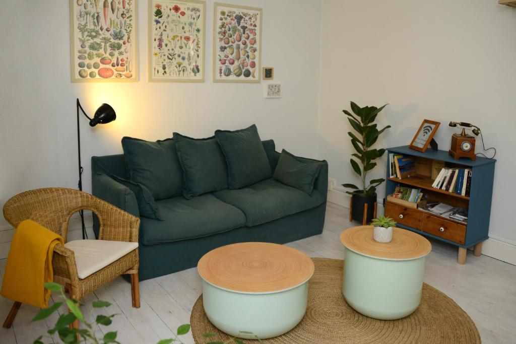 a living room with a green couch and a table at Le pied-à-terre du botaniste in Hauteville-Lompnes