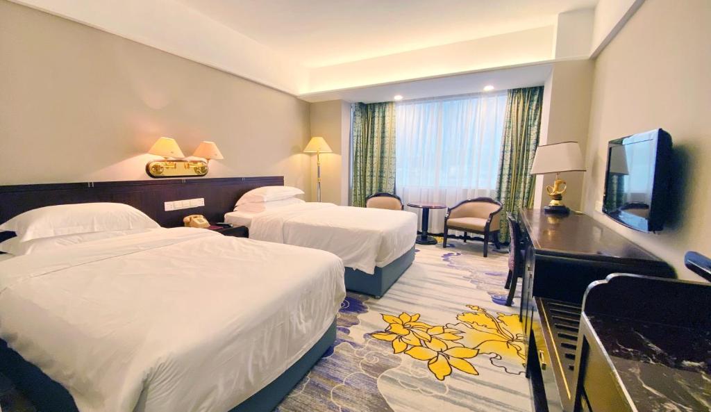 a hotel room with two beds and a television at Zhongshan International Hotel in Zhongshan