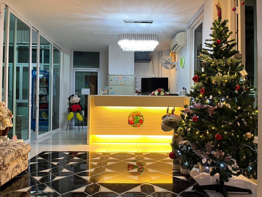 a living room with a christmas tree and a yellow bench at Papangkorn House in Suratthani