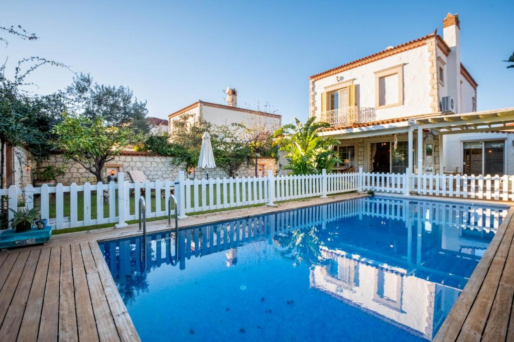 a house with a white fence and a swimming pool at Luxury Duplex Villa w Pool and Garden in Alacati in Alacati