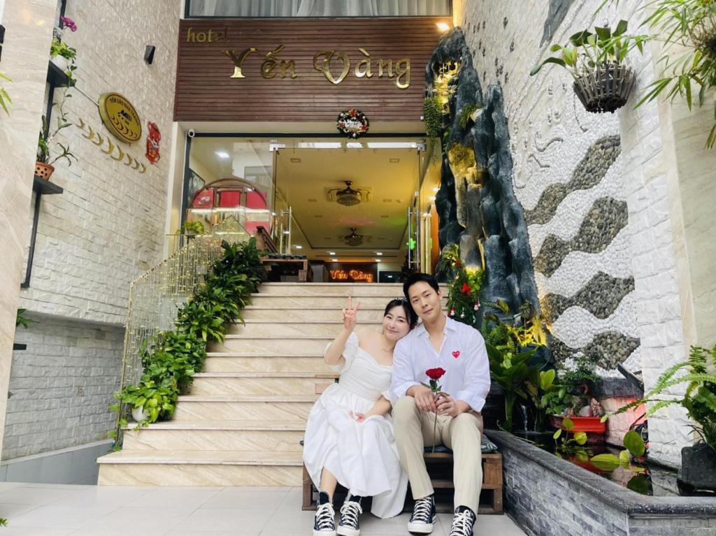 un hombre y una mujer sentados en las escaleras de un edificio en Yen Vang Hotel & Apartment Nha Trang, en Nha Trang