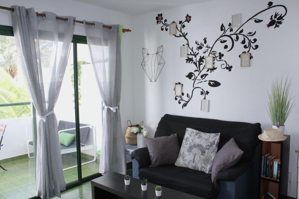 een woonkamer met een bank en een kroonluchter bij Surycan Tropical Garden Apartment in Playa del Inglés