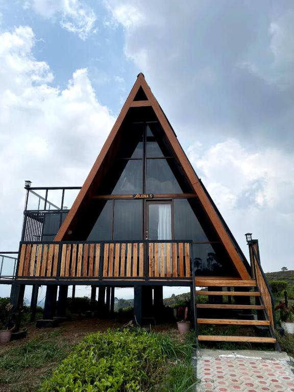 a frame house with a thatched roof at Nimo Tea Resort in Tanara
