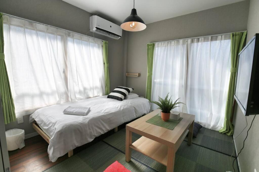 a bedroom with a bed and a table and windows at Edogawa Japanese Style Apartment 202 has direct access to Akihabara and Shinjuku, with convenient transportation and free WiFi in Tokyo