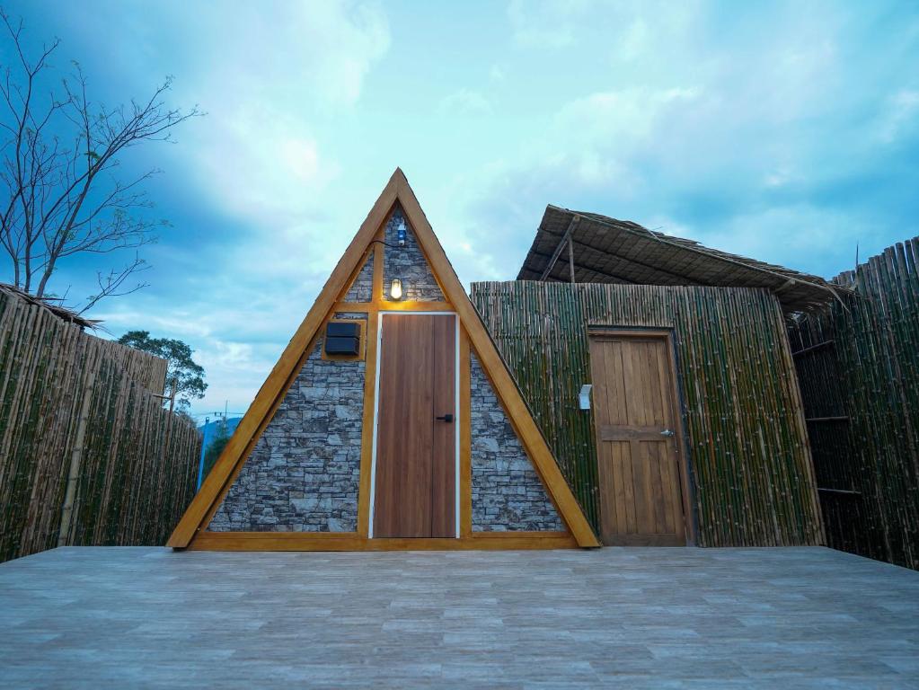 a triangular house with a door and a stone wall at RoomQuest Kid Tung Khao in Ban Huai Sok Noi