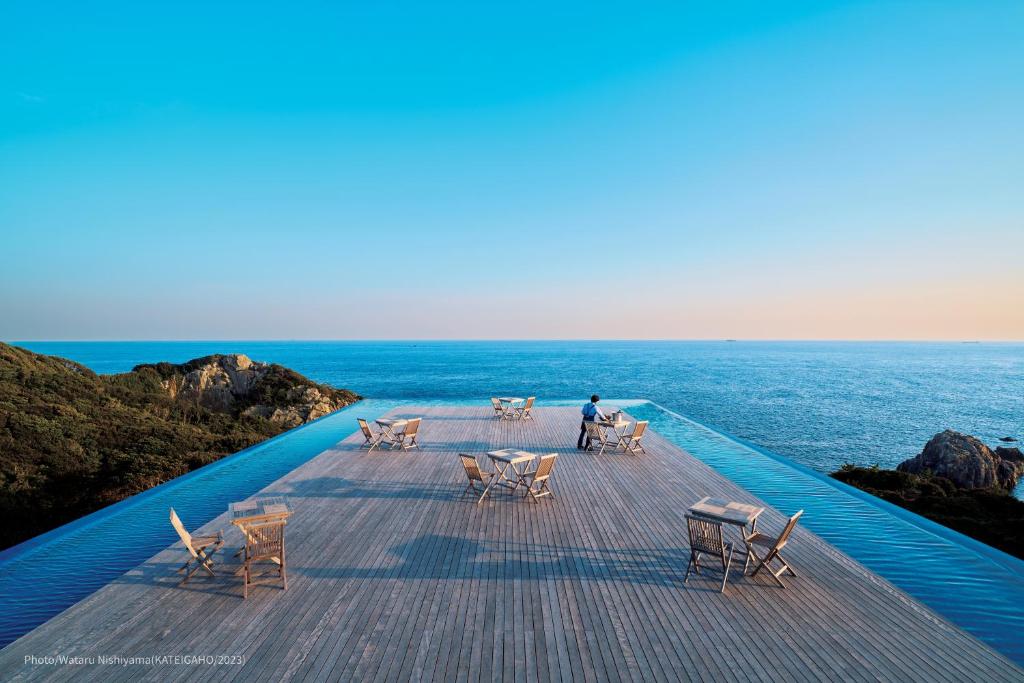 a man sitting on a deck looking at the ocean at TheMana Village in Tosashimizu