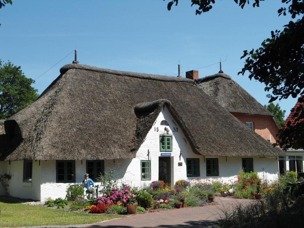 een huis met een rieten dak en bloemen bij Kathmeyers Landhaus Godewind in Sankt Peter-Ording