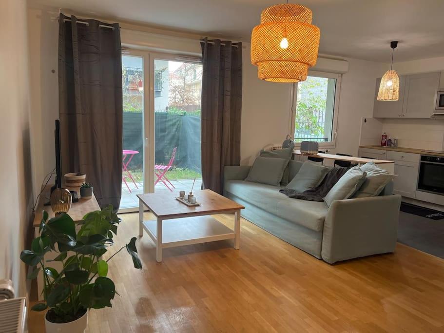 ein Wohnzimmer mit einem Sofa und einem Tisch in der Unterkunft Grand studio dans résidence récente in Vitry-sur-Seine