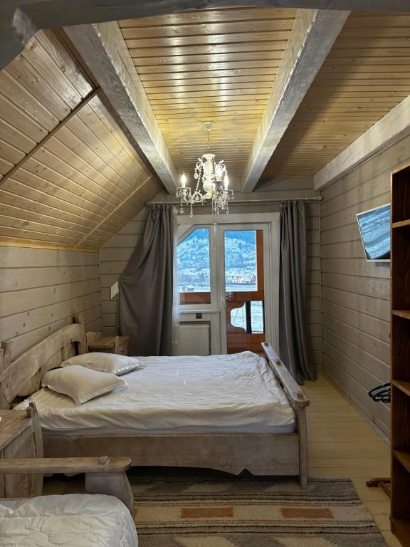 a bedroom with a large bed and a chandelier at Green hills in Verkhovyna