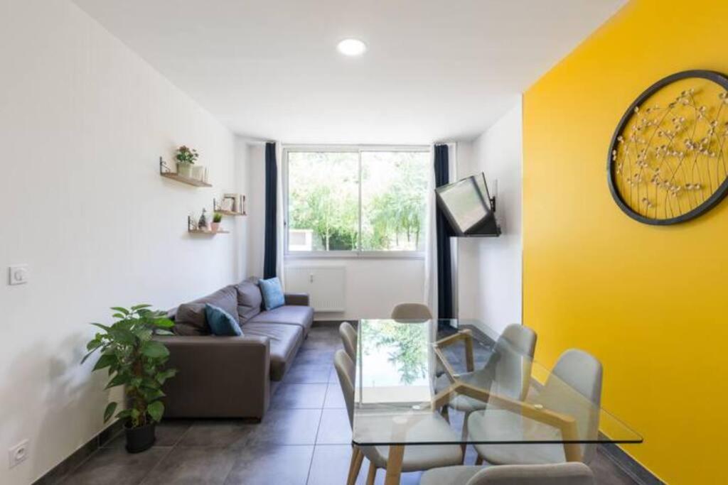 een woonkamer met een bank en een tafel bij Sereniva - Appartement Familial 2 chambres in Reims