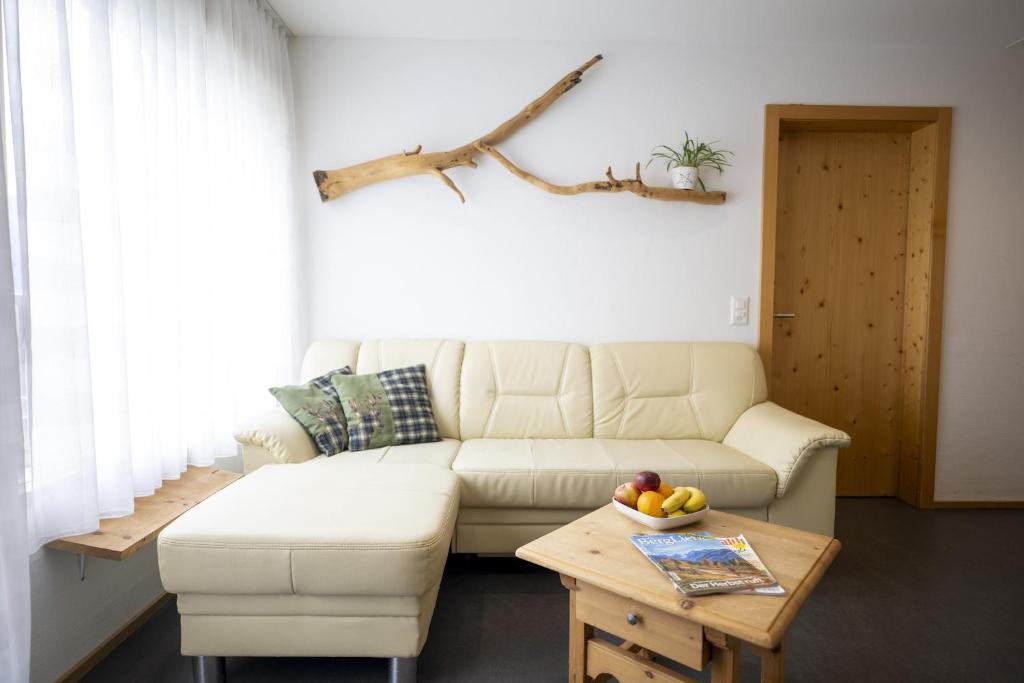 uma sala de estar com um sofá e uma mesa com uma taça de fruta em Chasa Bazzell em Ftan