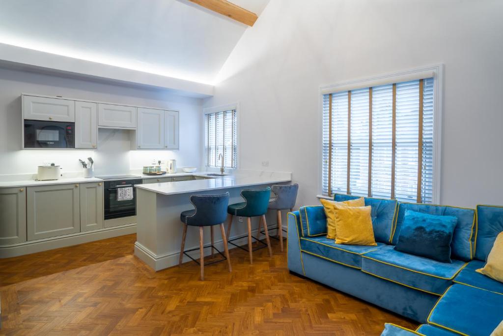 a living room with a blue couch and a kitchen at Hazelwick Apartment in Crawley