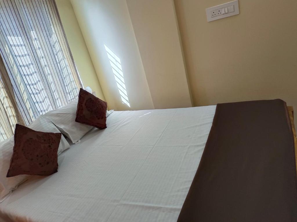 a bedroom with a bed with white sheets and two pillows at Royal Comforts in Mysore