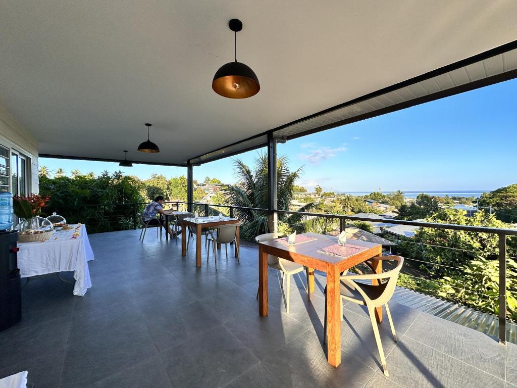 a dining room with tables and chairs on a balcony at Ononui Lodge Airport, Ocean-View, Private Bathroom and Balcony, Free WiFi and Parking, On-Site Car Rental in Faaa