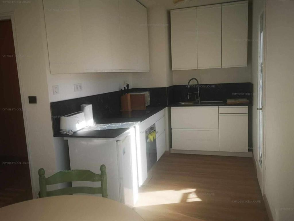 a kitchen with white cabinets and a sink and a chair at 4PA72 - Magnifique appartement pour 4 dans résidence avec piscine et parking in Collioure