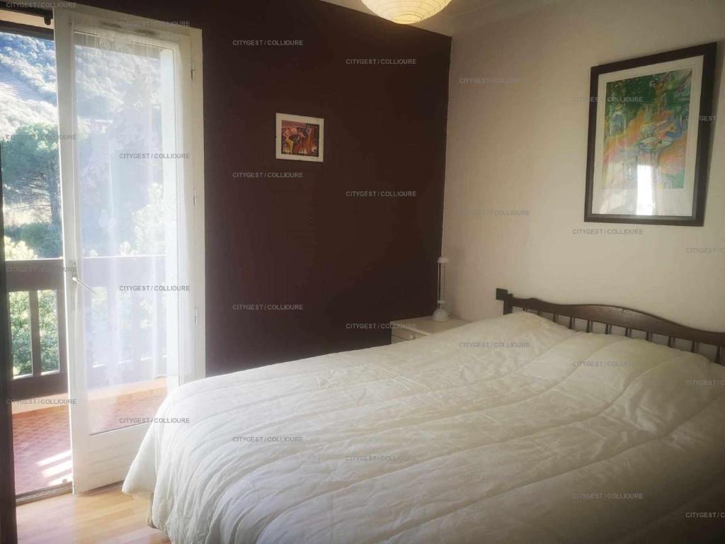 a bedroom with a white bed and a window at 4PA72 - Magnifique appartement pour 4 dans résidence avec piscine et parking in Collioure