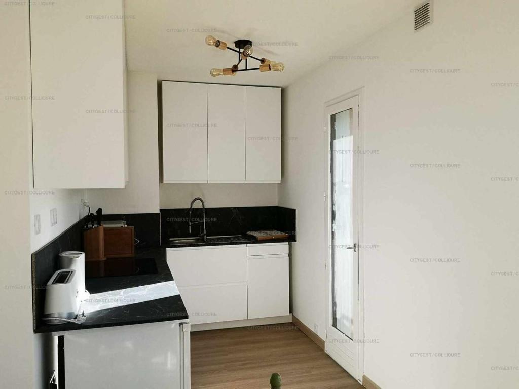 a kitchen with white cabinets and a ceiling fan at 4PA72 - Magnifique appartement pour 4 dans résidence avec piscine et parking in Collioure
