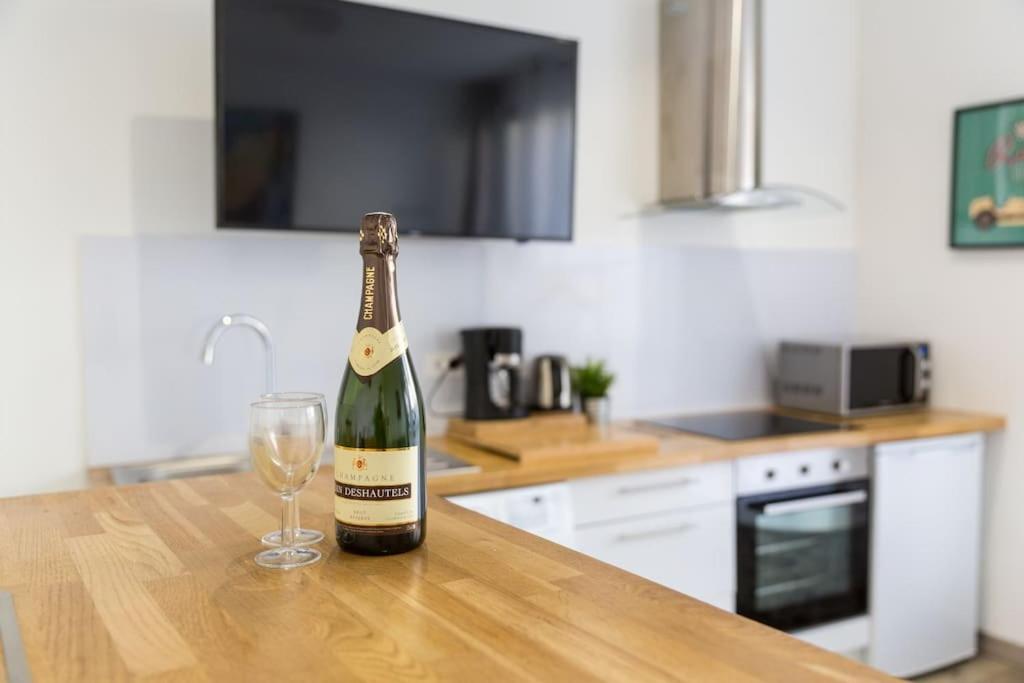 a bottle of champagne and a glass on a kitchen counter at Tranquilis - Studio hypercentre terrasse parking in Reims