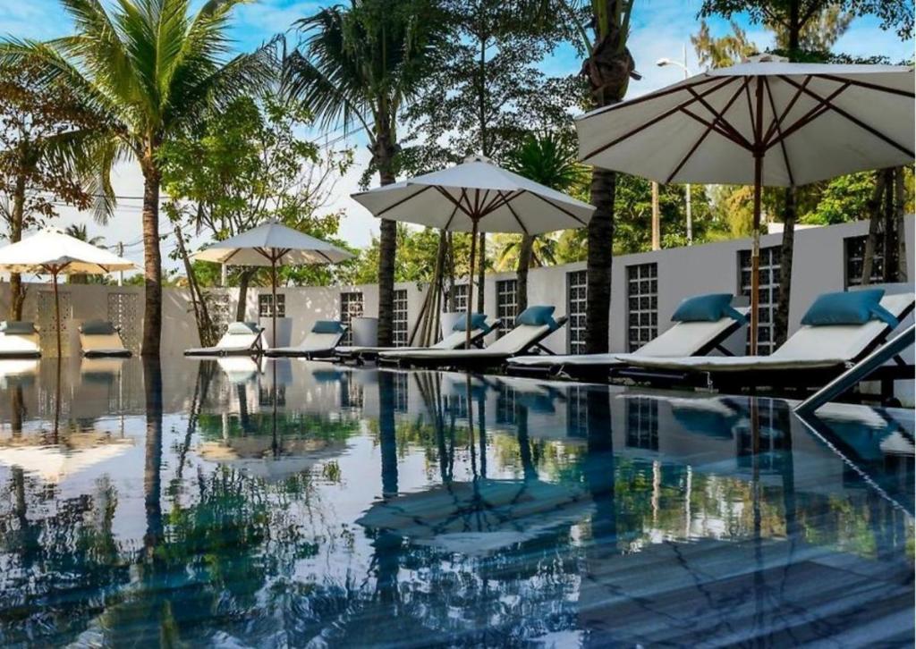 una piscina con tumbonas y sombrillas en HA Hotel Apartments Ocean Front, en Hoi An