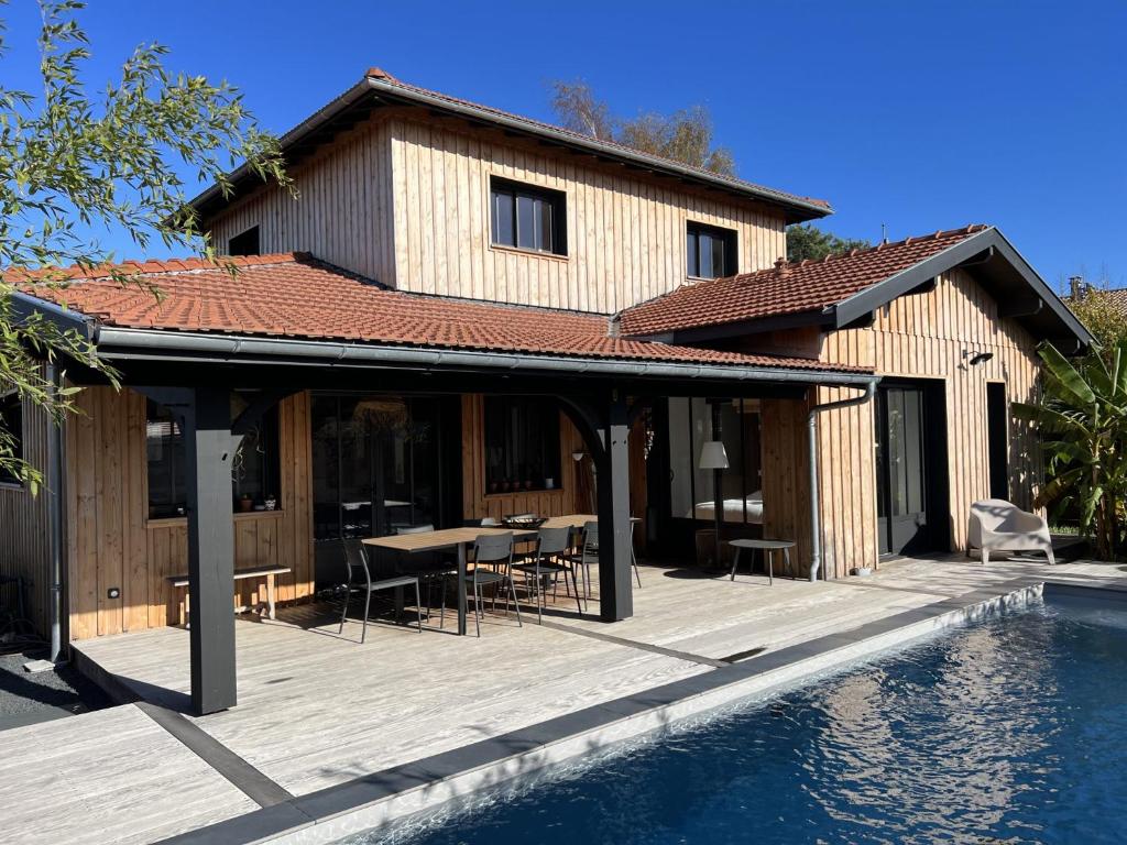 uma casa com um deque ao lado de uma piscina em Villa avec piscine chauffée em Arès