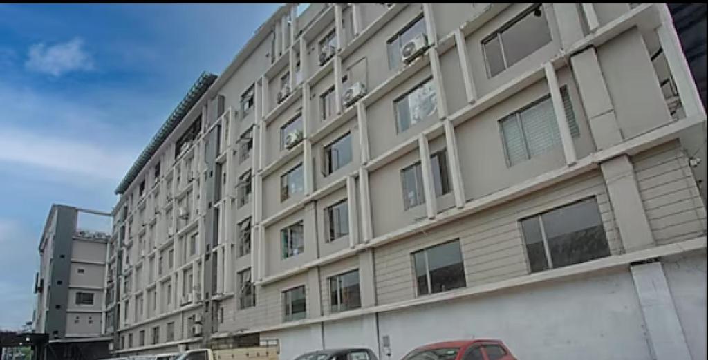 a large white building with cars parked in front of it at Yashshree Milestone in Siliguri