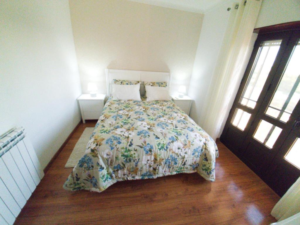 a bedroom with a bed with a floral bedspread at Caldas da Rainha's Green & Brown in Caldas da Rainha