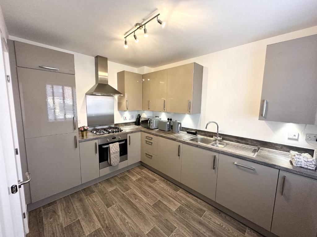 a kitchen with white cabinets and wooden floors at Fairway Villa in Stafford