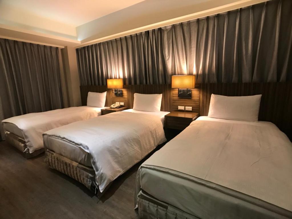 a hotel room with two beds and two lamps at Paris Business Hotel in Kaohsiung