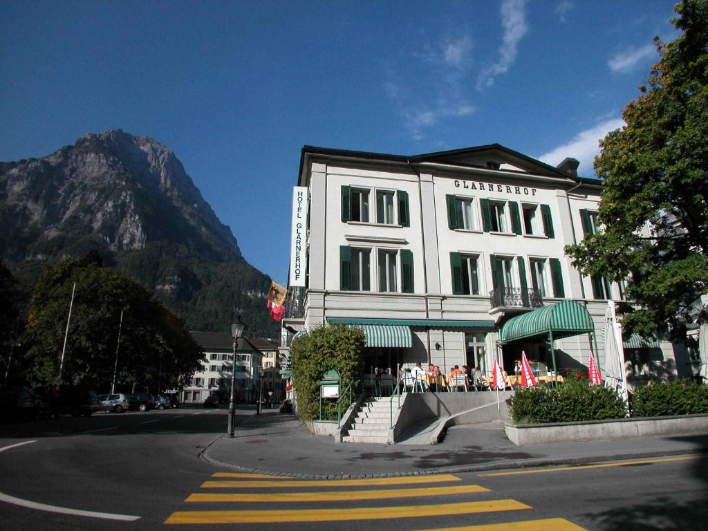 a white building with a restaurant in front of a mountain at Hotel Post Glarnerhof in Glarus