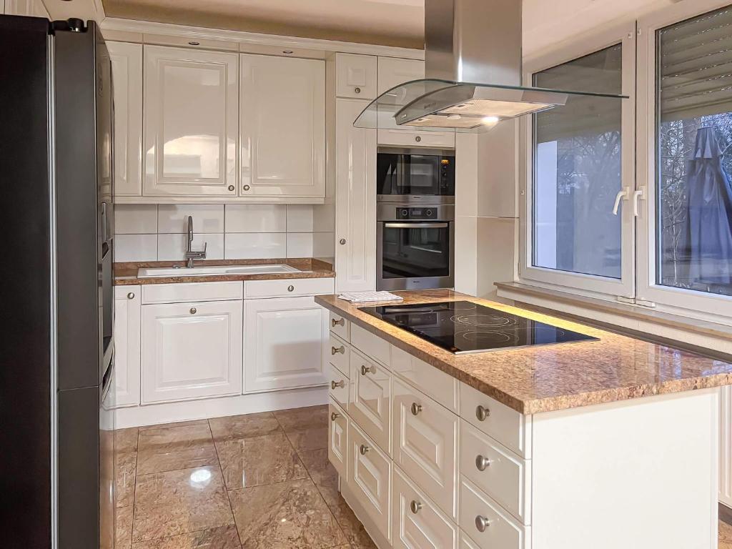 a kitchen with white cabinets and a black refrigerator at T&K Apartments - Erkrath - 4 Zimmer Apartments in Erkrath